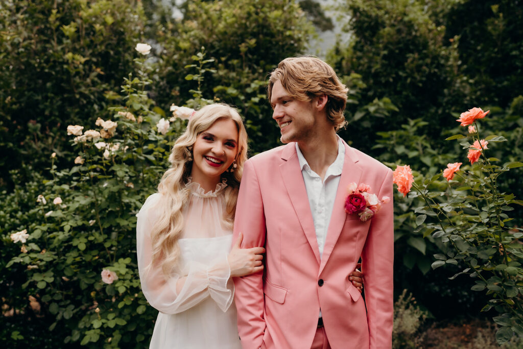 Couple in pink at mcgill rose garden in charlotte surrounded by pink roses