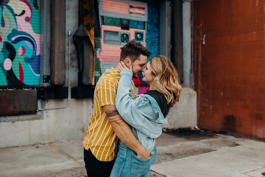 couple kissing in front of murals at Camp North End in Charlotte