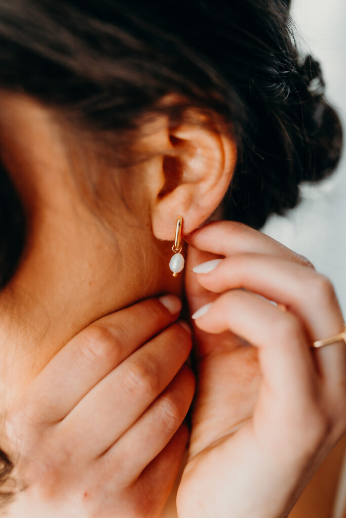 bride putting on pearl earring