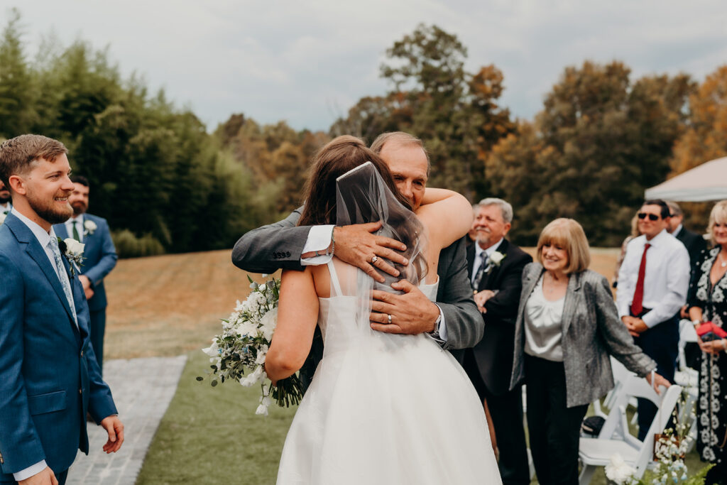 wedding ceremony with bride hugging dad and he gives her away