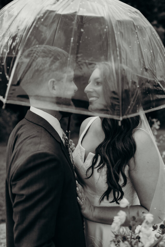 black and white photo of a couple under an umbrella in the rain