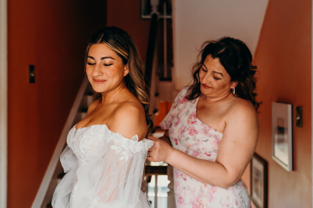 bride getting into dress with sister