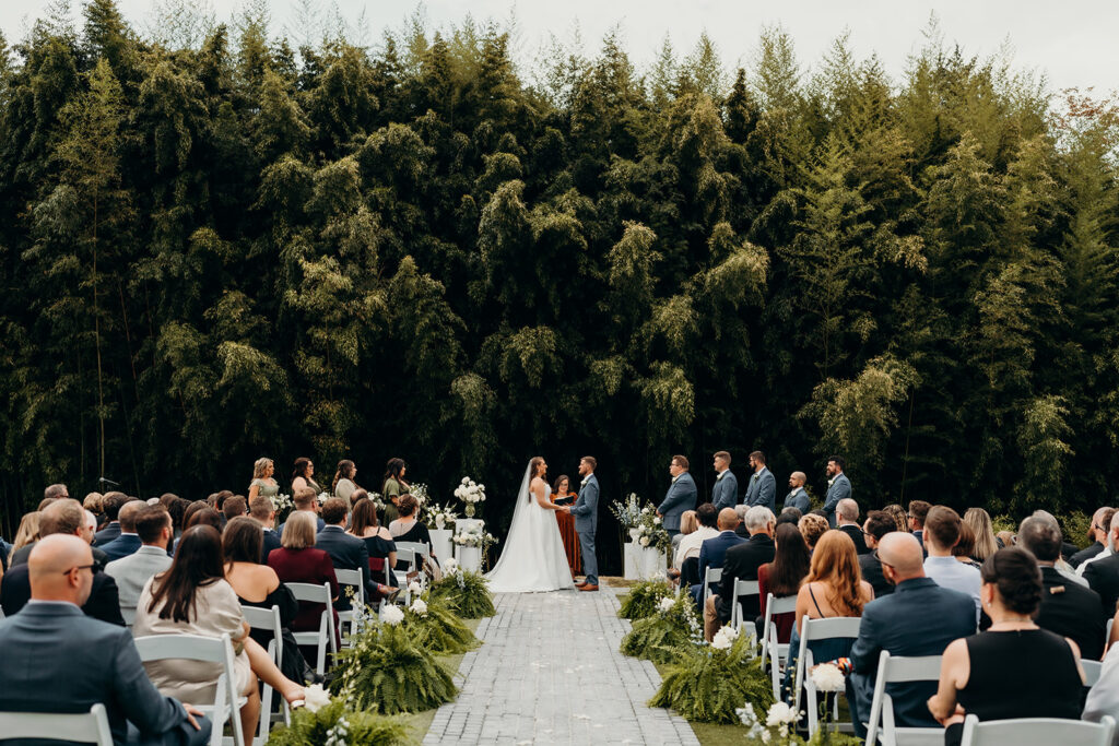 couple getting married during ceremony under bamboo trees