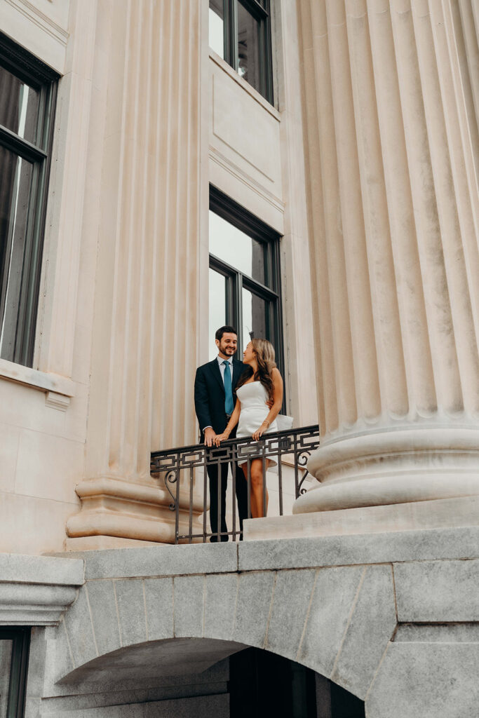 couple in white dress and navy blue suit and tie at classic courthouse building in uptown charlotte