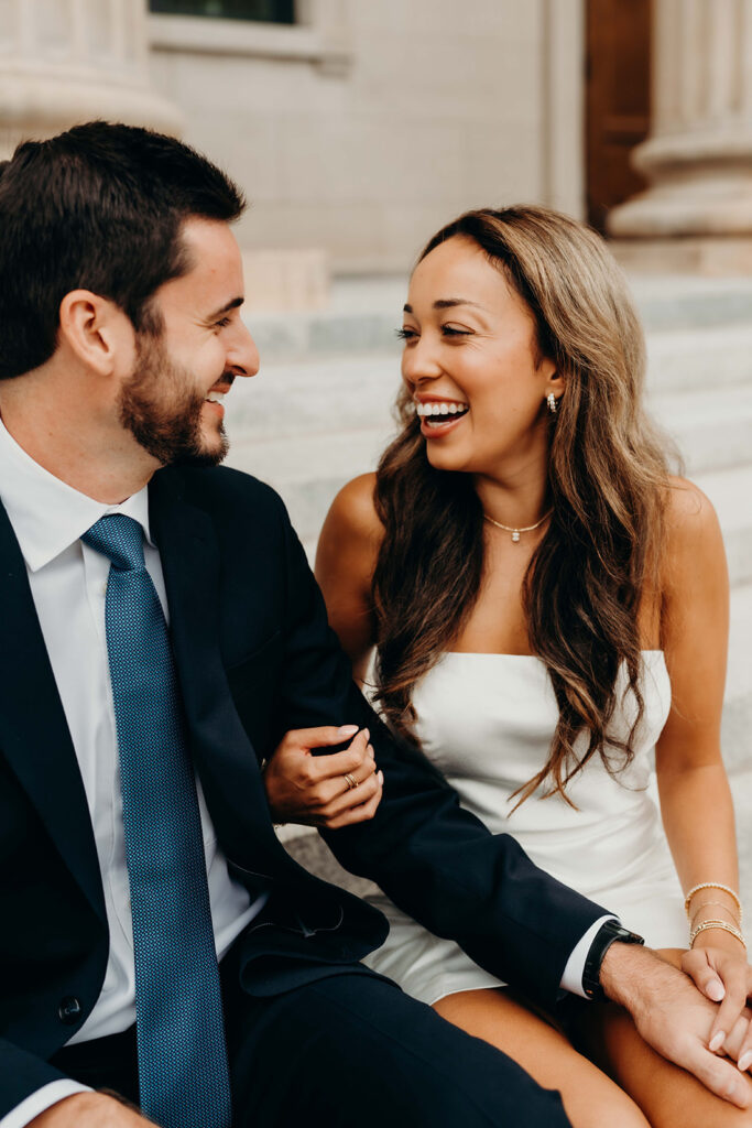couple in white dress and navy blue suit and tie at classic courthouse building in uptown charlotte