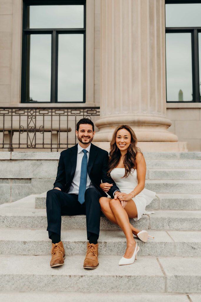 couple in white dress and navy blue suit and tie at classic courthouse building in uptown charlotte