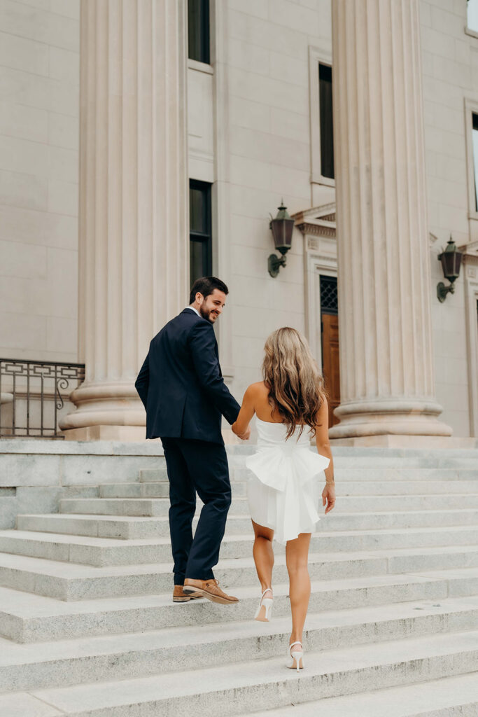 couple in white dress and navy blue suit and tie at classic courthouse building in uptown charlotte