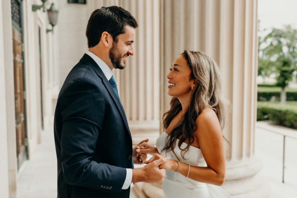 couple in white dress and navy blue suit and tie at classic courthouse building in uptown charlotte