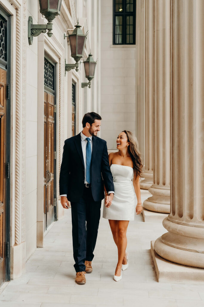 couple in white dress and navy blue suit and tie at classic courthouse building