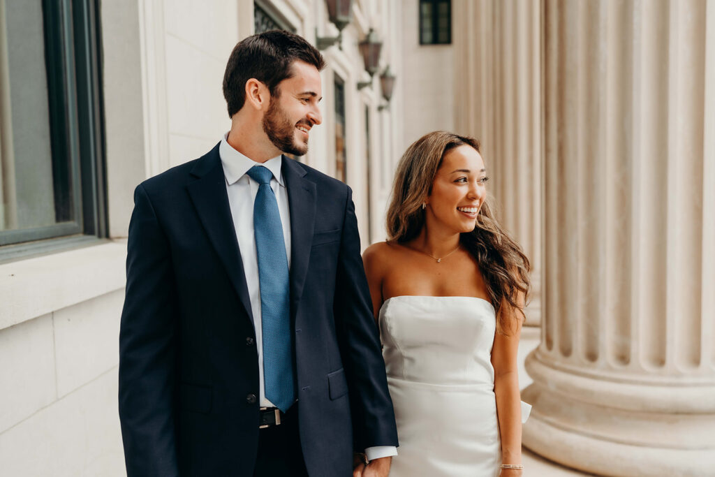 couple in white dress and navy blue suit and tie at classic courthouse building