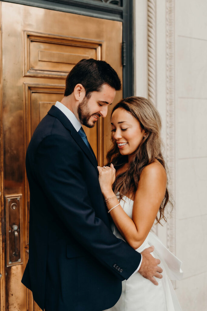 couple in white dress and navy blue suit and tie at classic courthouse building in uptown charlotte