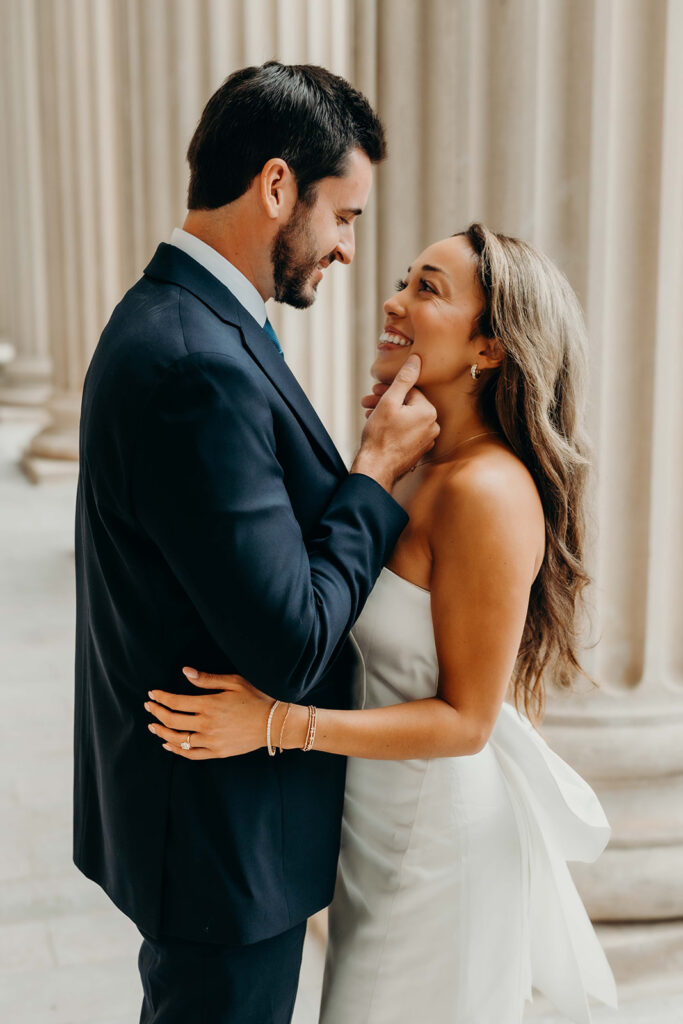 couple in white dress and navy blue suit and tie at classic courthouse building