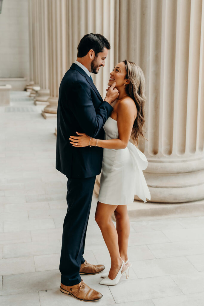 couple in white dress and navy blue suit and tie at classic courthouse building in uptown charlotte