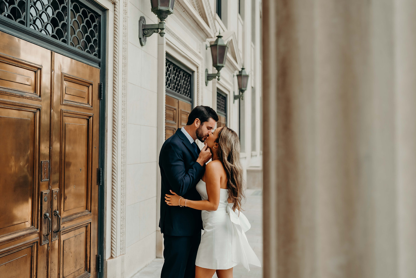 couple in white dress and navy blue suit and tie at classic courthouse building in uptown charlotte