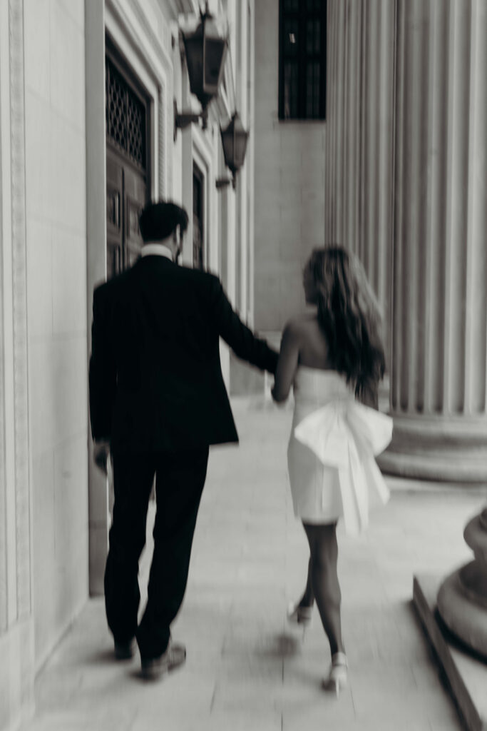 couple in white dress and navy blue suit and tie at classic courthouse building