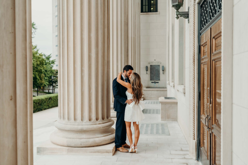 couple in white dress and navy blue suit and tie at classic courthouse building