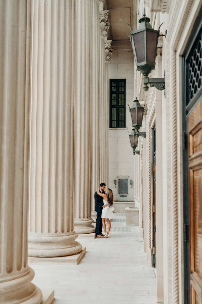 couple in white dress and navy blue suit and tie at classic courthouse building