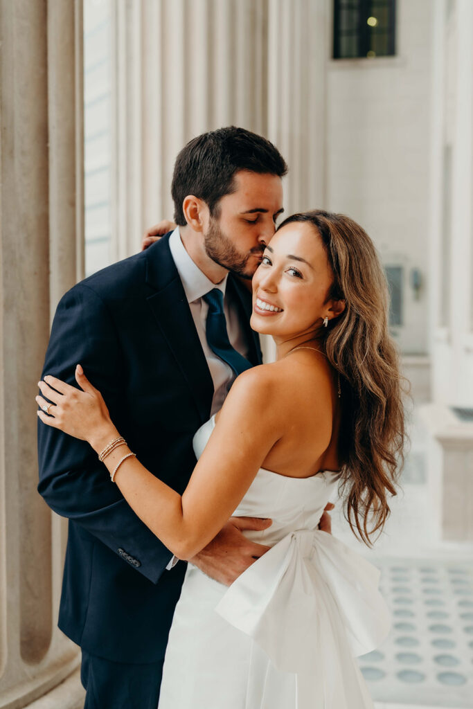 couple in white dress and navy blue suit and tie at classic courthouse building