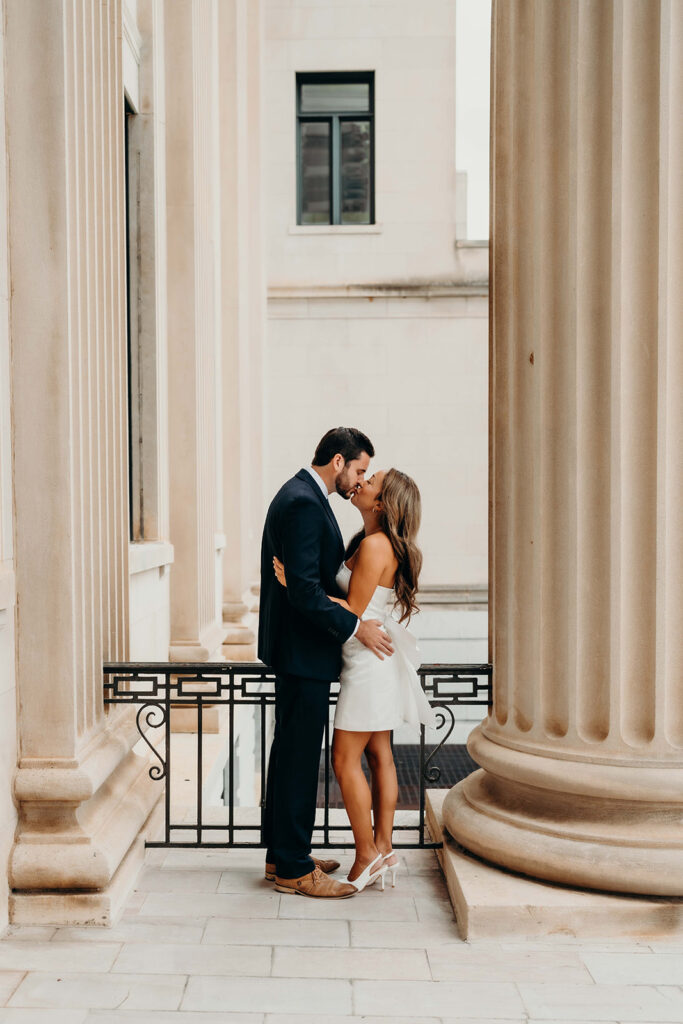 couple in white dress and navy blue suit and tie at classic courthouse building in uptown charlotte