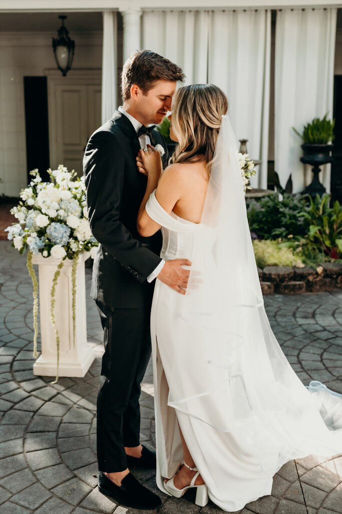 Summer wedding ceremony in secret private courtyard on a sunny day with lush greenery and blue flowers walking down aisle
