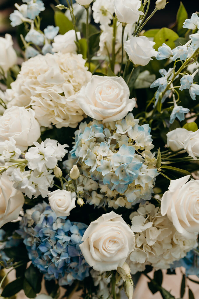 Summer wedding ceremony in secret private courtyard on a sunny day with lush greenery and blue flowers