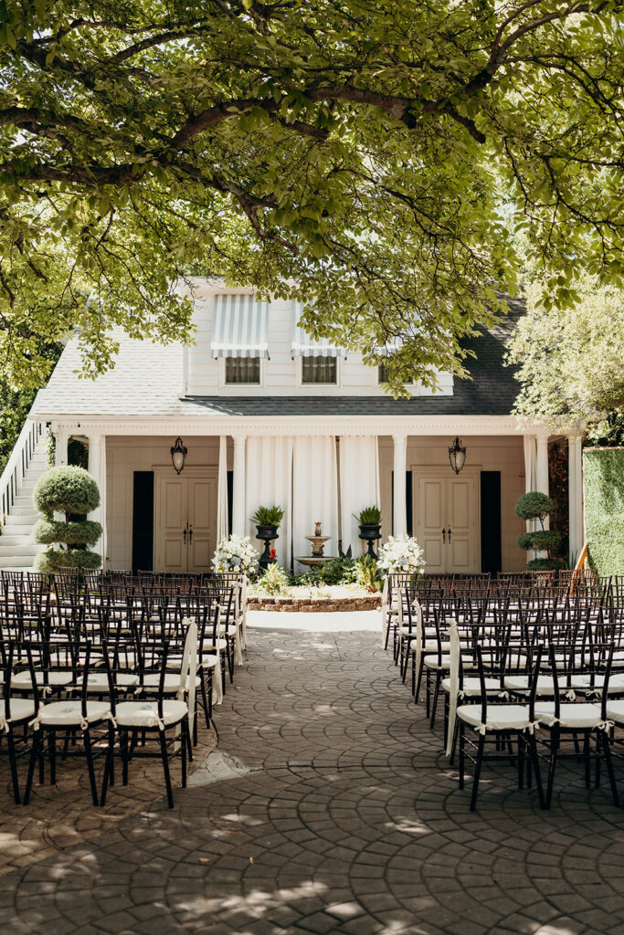 Summer wedding ceremony in secret private courtyard on a sunny day with lush greenery and blue flowers