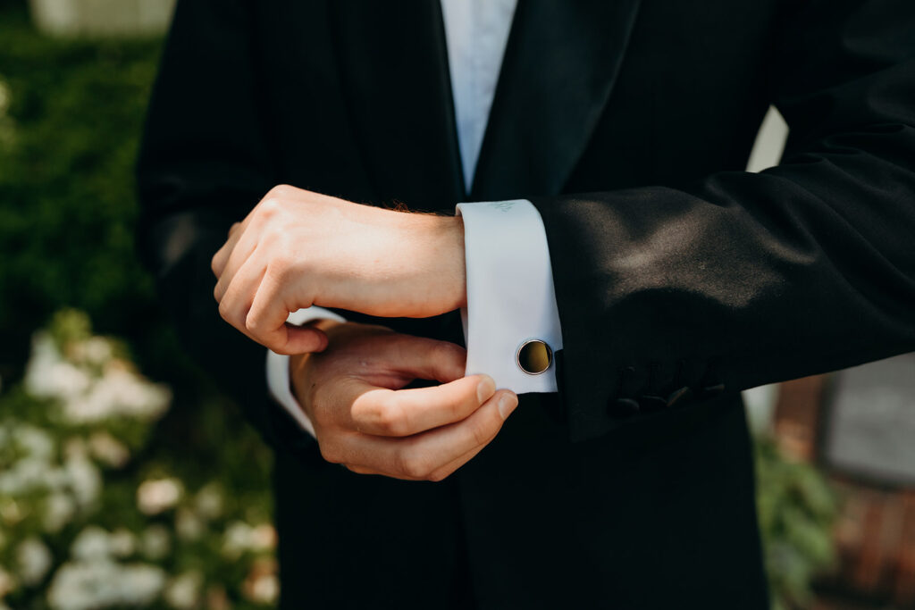 Groom getting ready photos outside with black suit