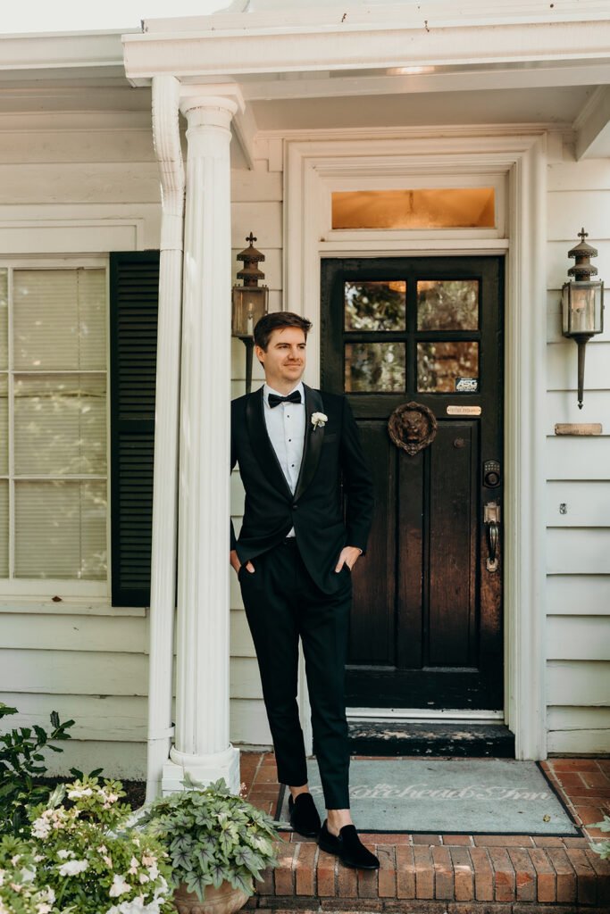 Groom getting ready photos outside with black suit