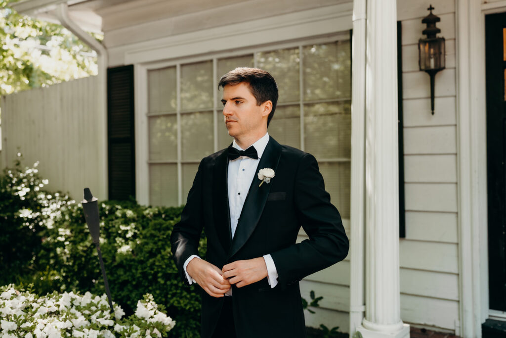 Groom getting ready photos outside with black suit