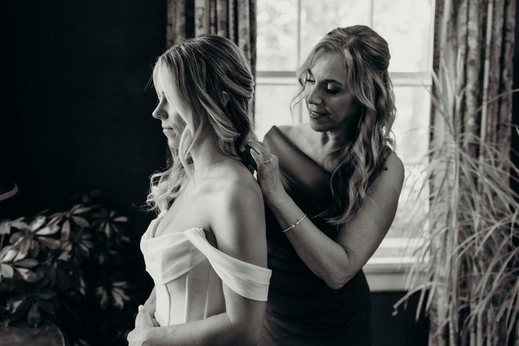 Bride getting into dress with mom helping