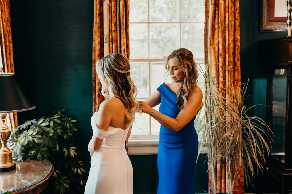 Bride getting into dress with mom helping