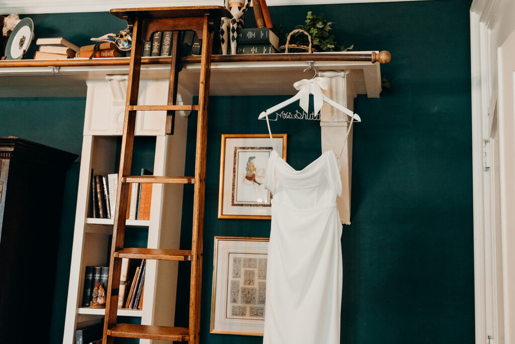 Getting ready photos with bride's dress hanging on hanger 