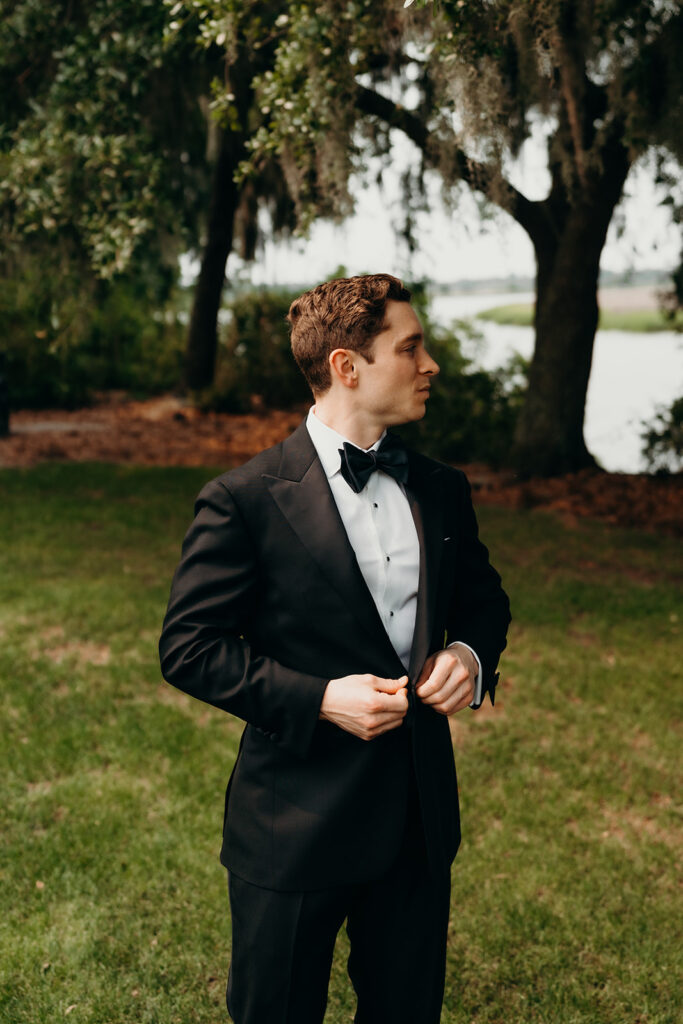 groom getting ready outdoors by the river at magnolia plantation