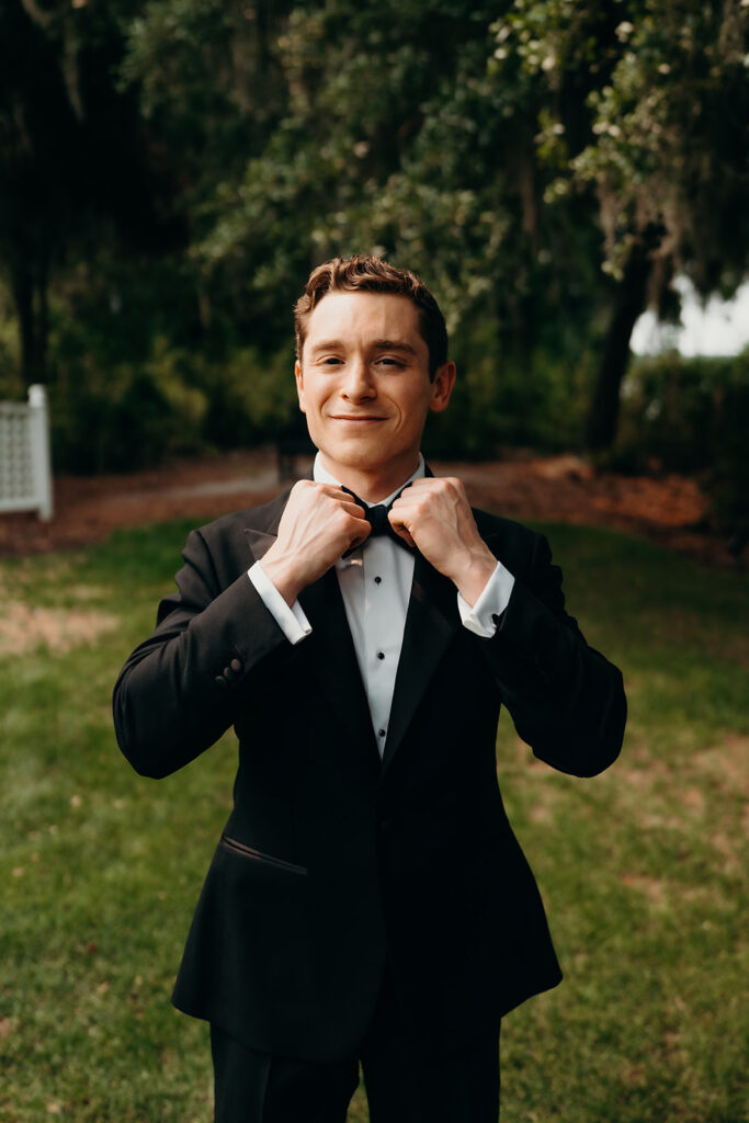 groom getting ready outdoors by the river at magnolia plantation