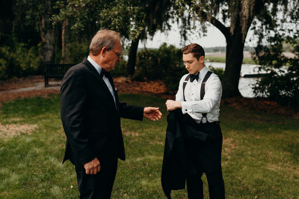 groom getting ready outdoors by the river at magnolia plantation