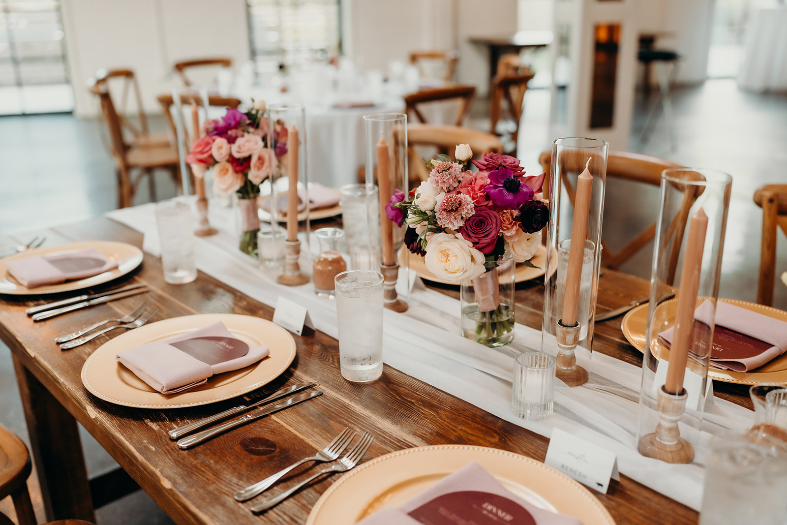 photo of a wedding table reception set up with gold chargers, purple invites, and pink and purple florals