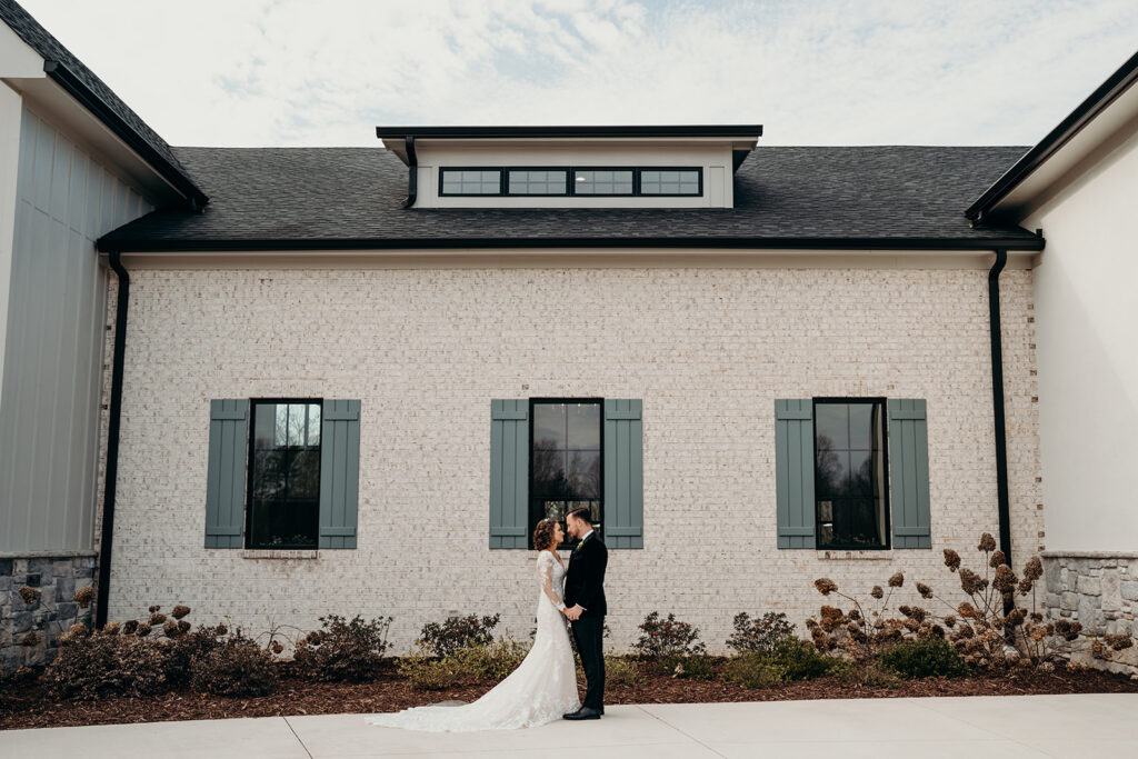couple holding each other in front of a modern barn