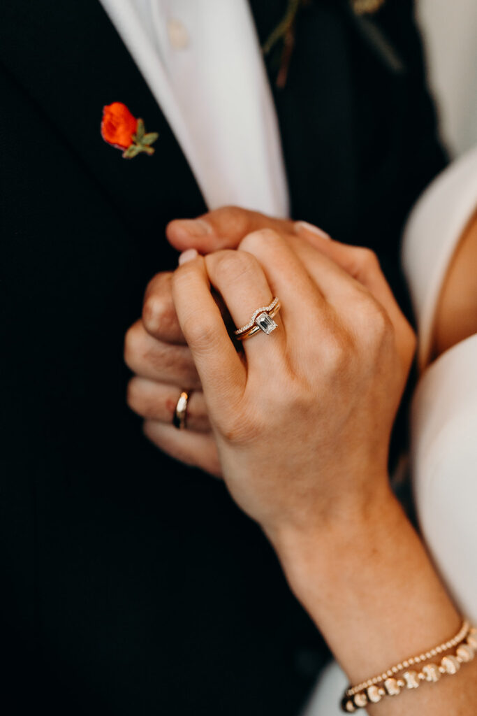 couple holding hands with wedding bands showing