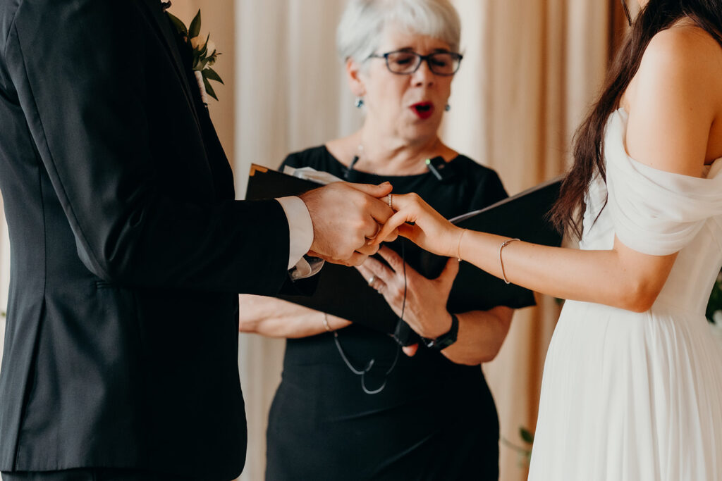 couple exchanging rings during ceremony at melrose knitting mill