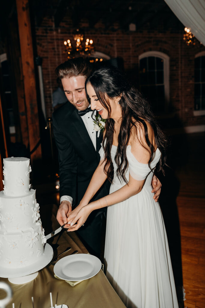 couple cutting the cake during their reception at Melrose Knitting Mill