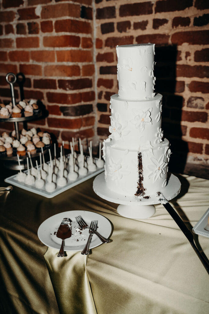three tier cake after cake cutting with slice on table at Melrose Knitting Mill