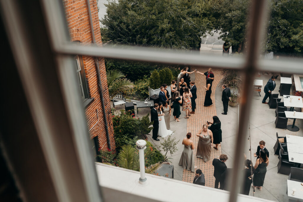 people socializing at couples portraits outside melrose knitting mill during cocktail hour