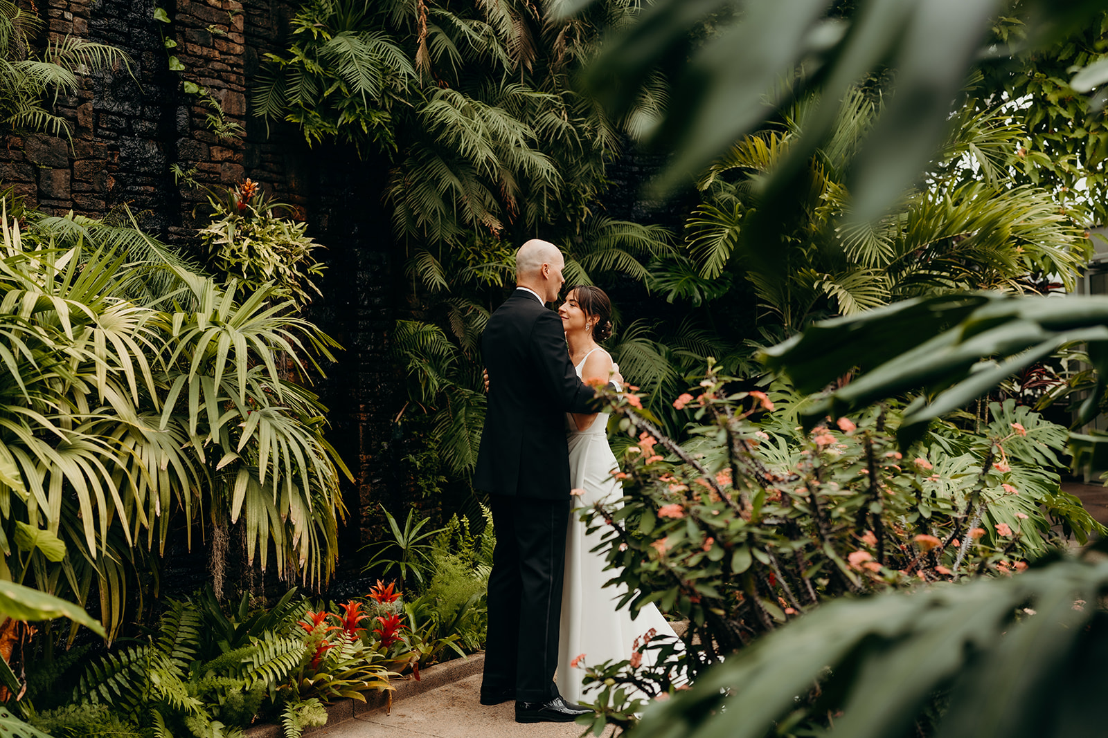 couple standing in Daniel Stowe Botanical Garden under the lush greenery while they hold each other