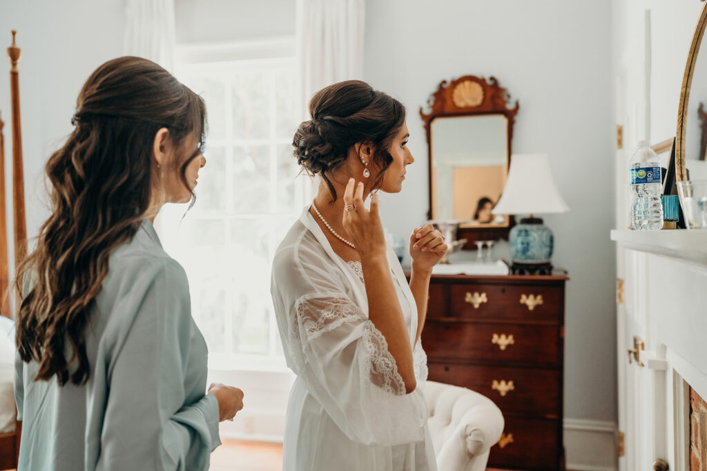 bride getting ready as she adjusts her earrings at rose hill estate's bridal suite