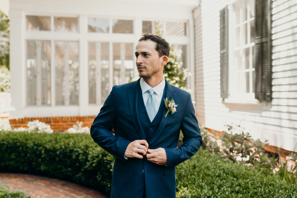 groom putting on jacket outside of rose hill estate