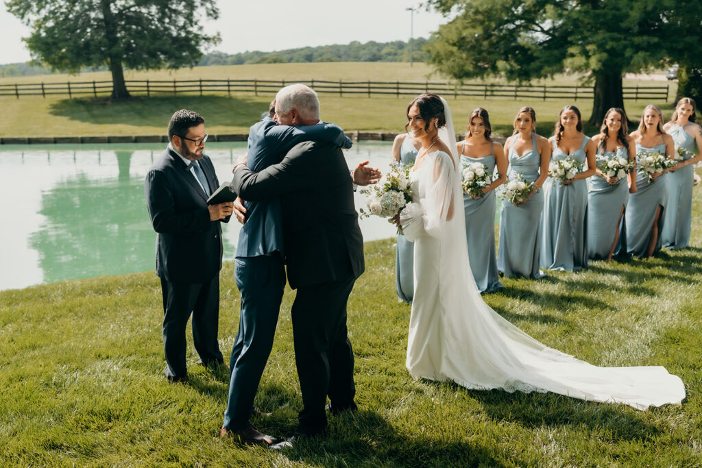 bride being given away by father at pond at the rose hill estate wedding