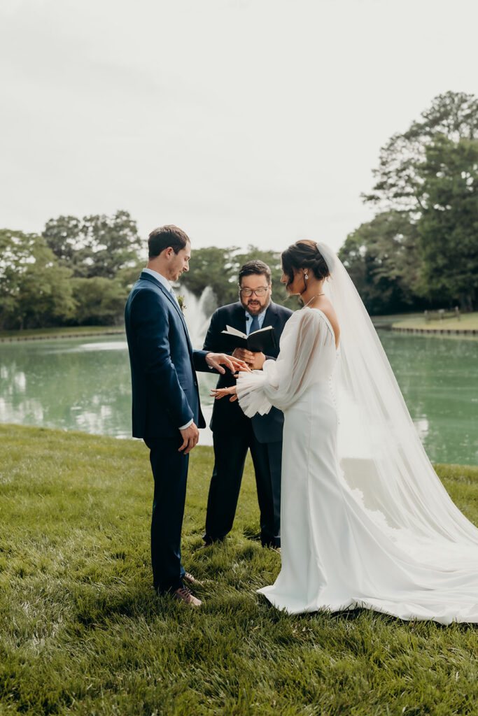bride and groom exchanging vows in front of the pond ceremony at their rose hill estate wedding