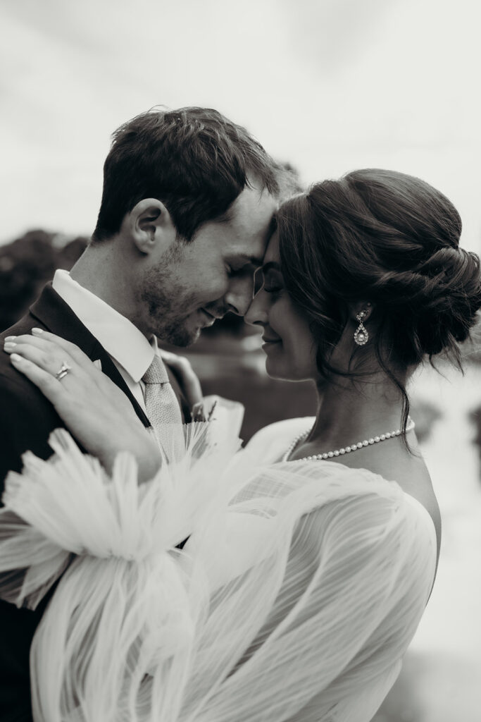 bride and groom holding each other close in front of the pond at their rose hill estate wedding