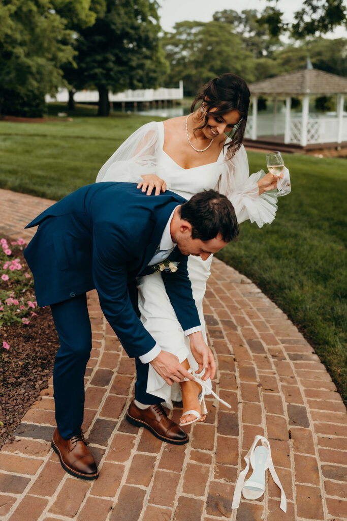 groom helping the bride take her shoes off at their rose hill estate wedding