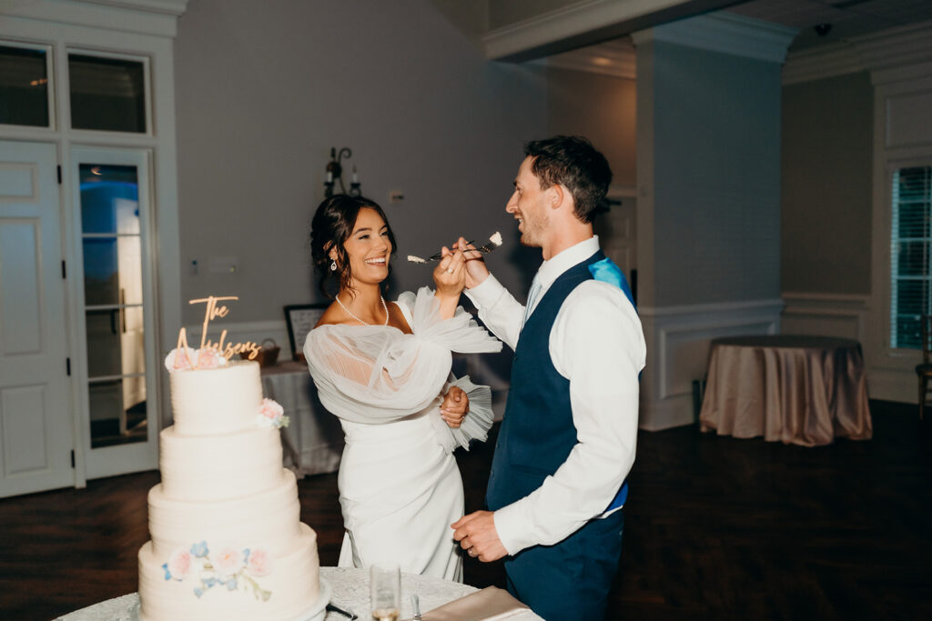 bride and groom feeding each other cake during the cake cutting